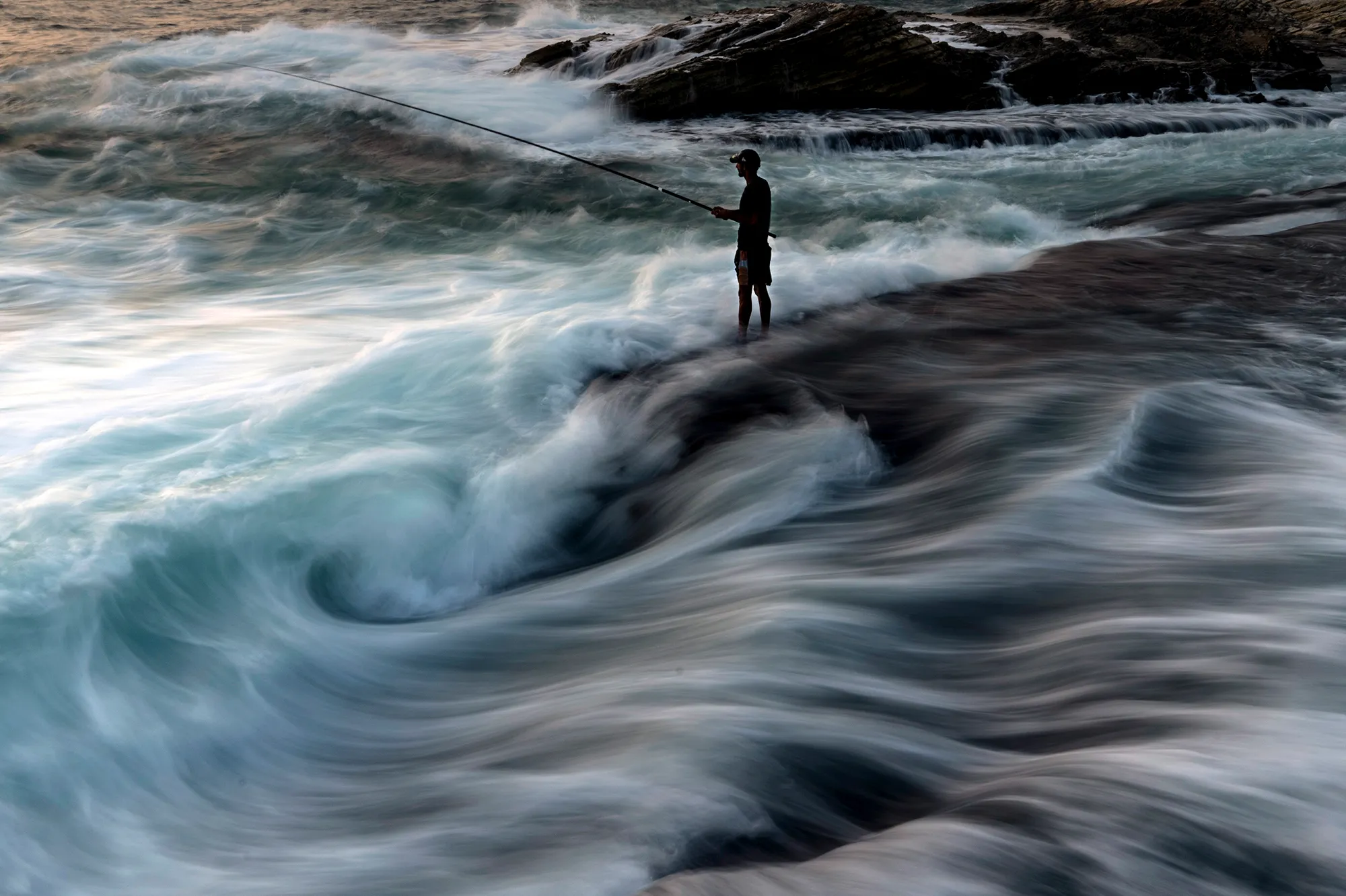 long exposure photo of person standing in front of waves